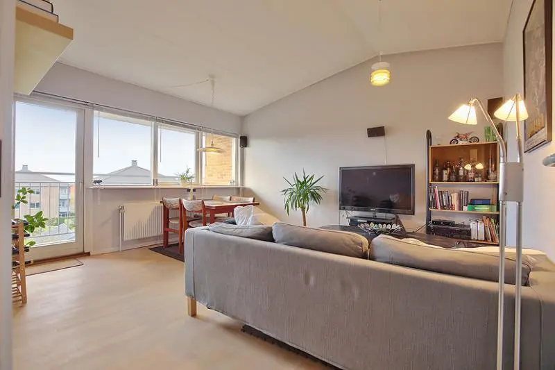 Lys stue med grå sofa og store vinduer